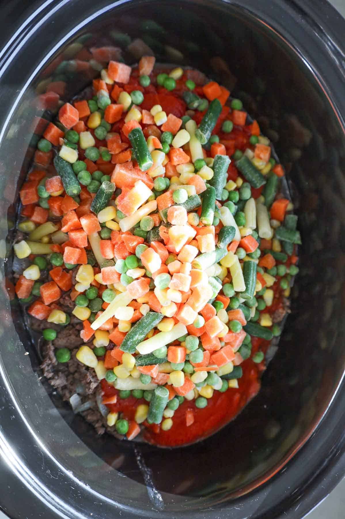 frozen mixed vegetables on top of diced tomatoes, tomato sauce and ground beef in a slow cooker
