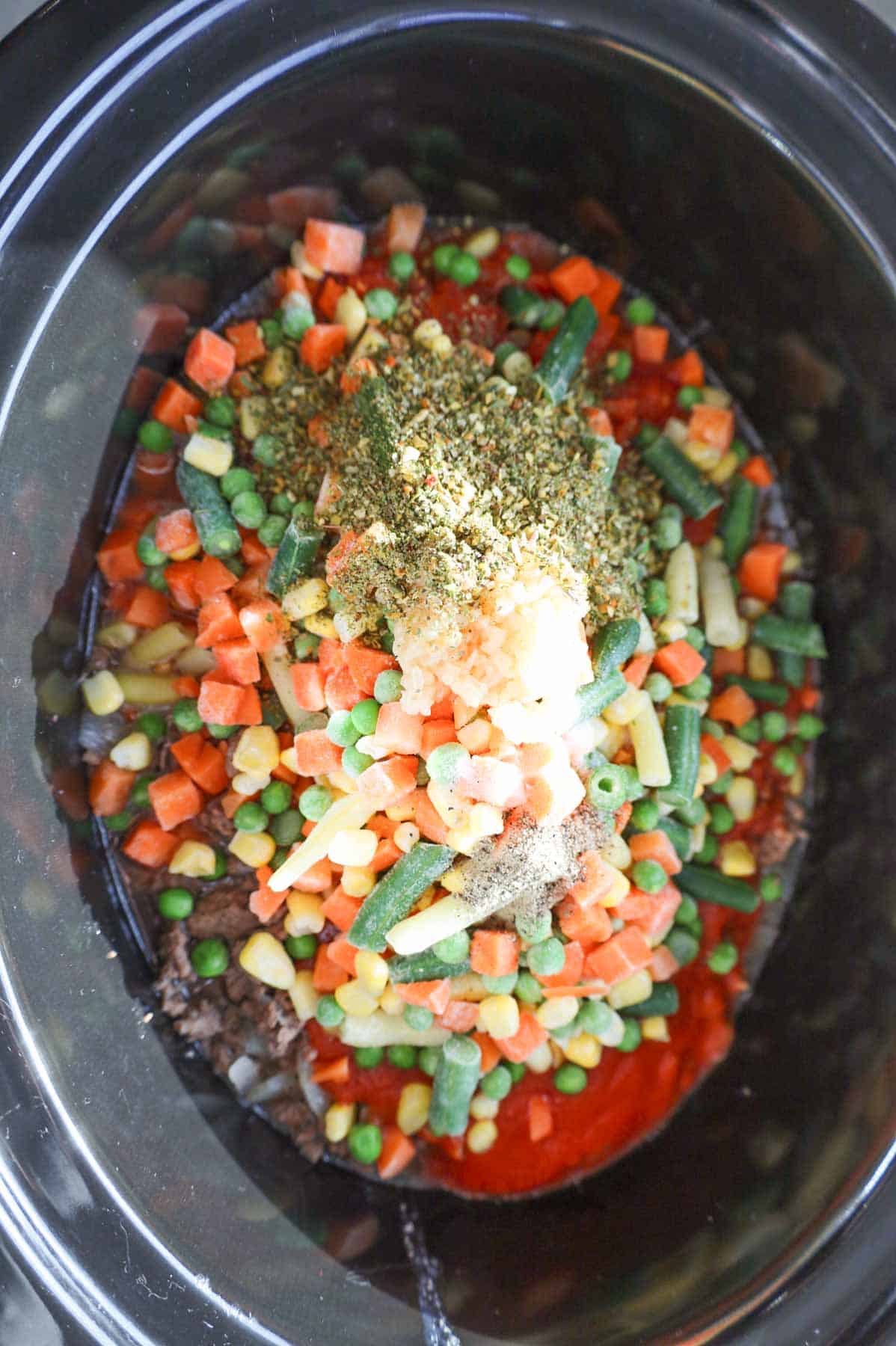 minced garlic and seasonings on top of frozen mixed veggies in a crock pot