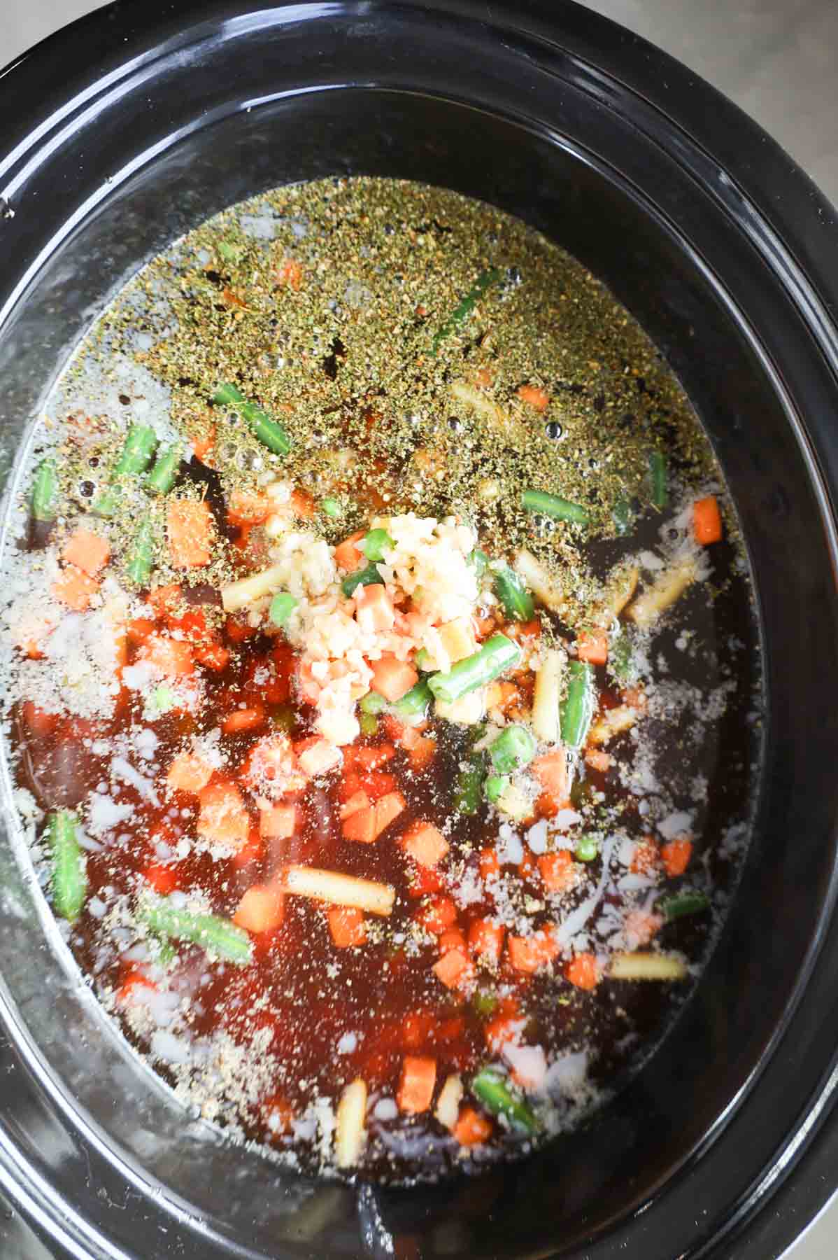 beef broth added to crock pot with frozen mixed veggies, diced tomatoes and cooked ground beef