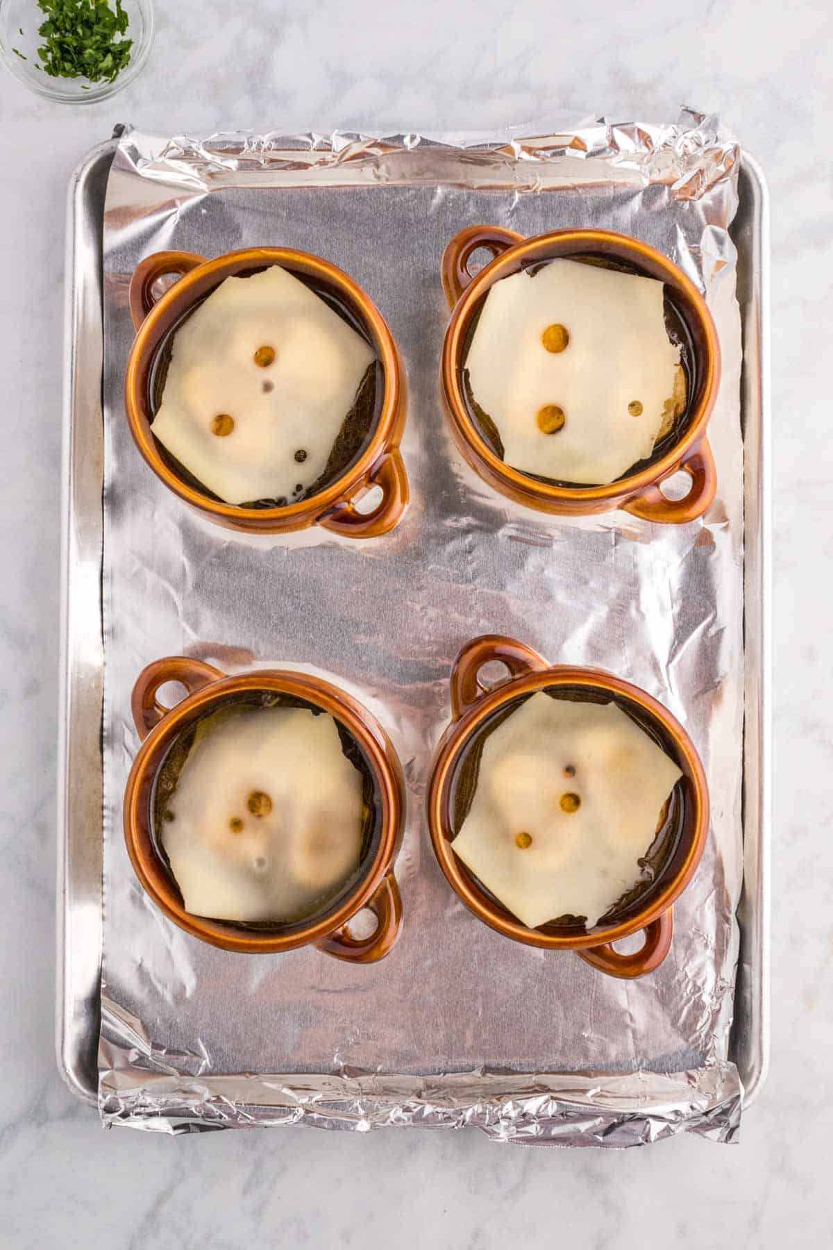Swiss cheese slices on top of French onion soup before broiling