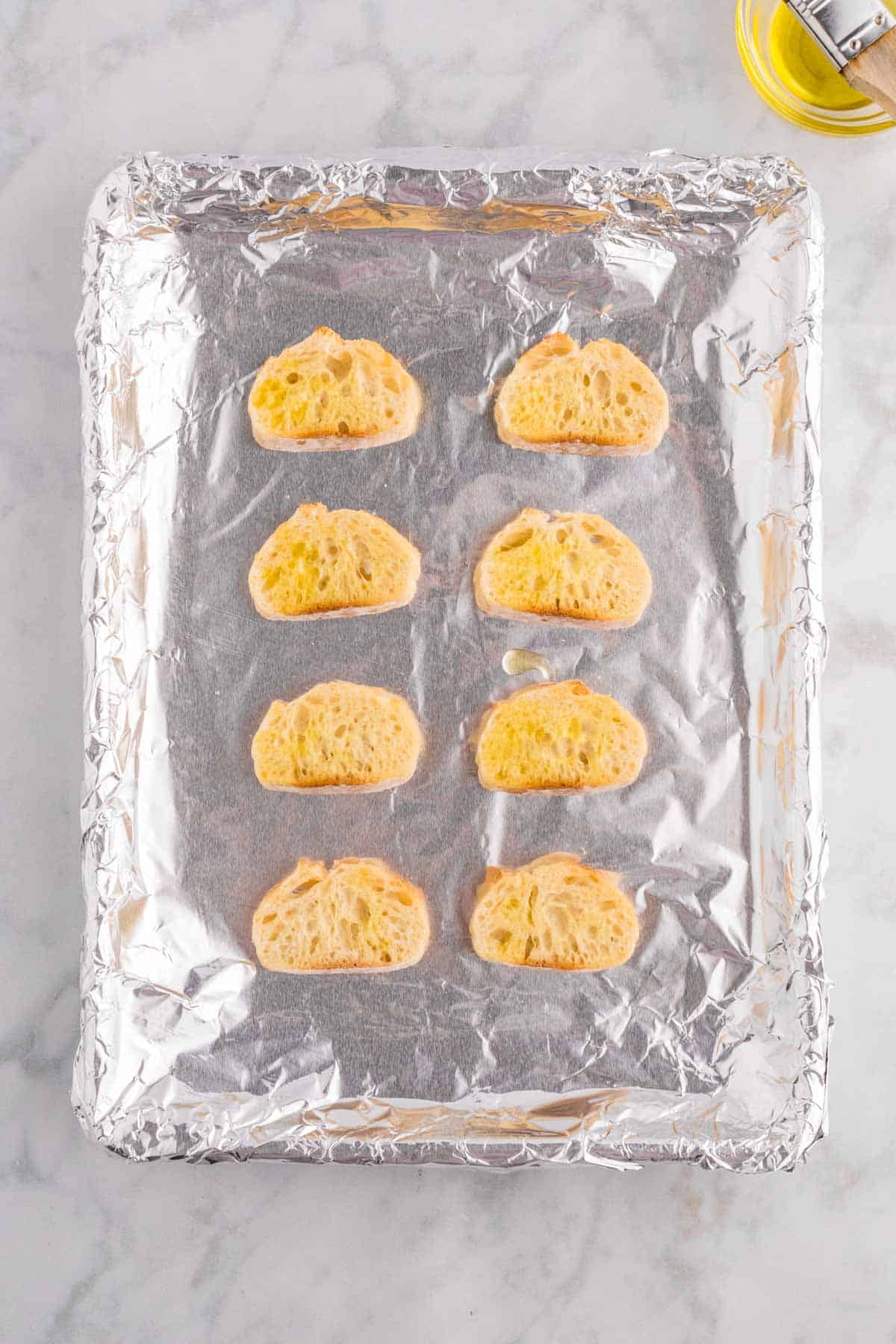 French baguette slices on a foil lined baking sheet