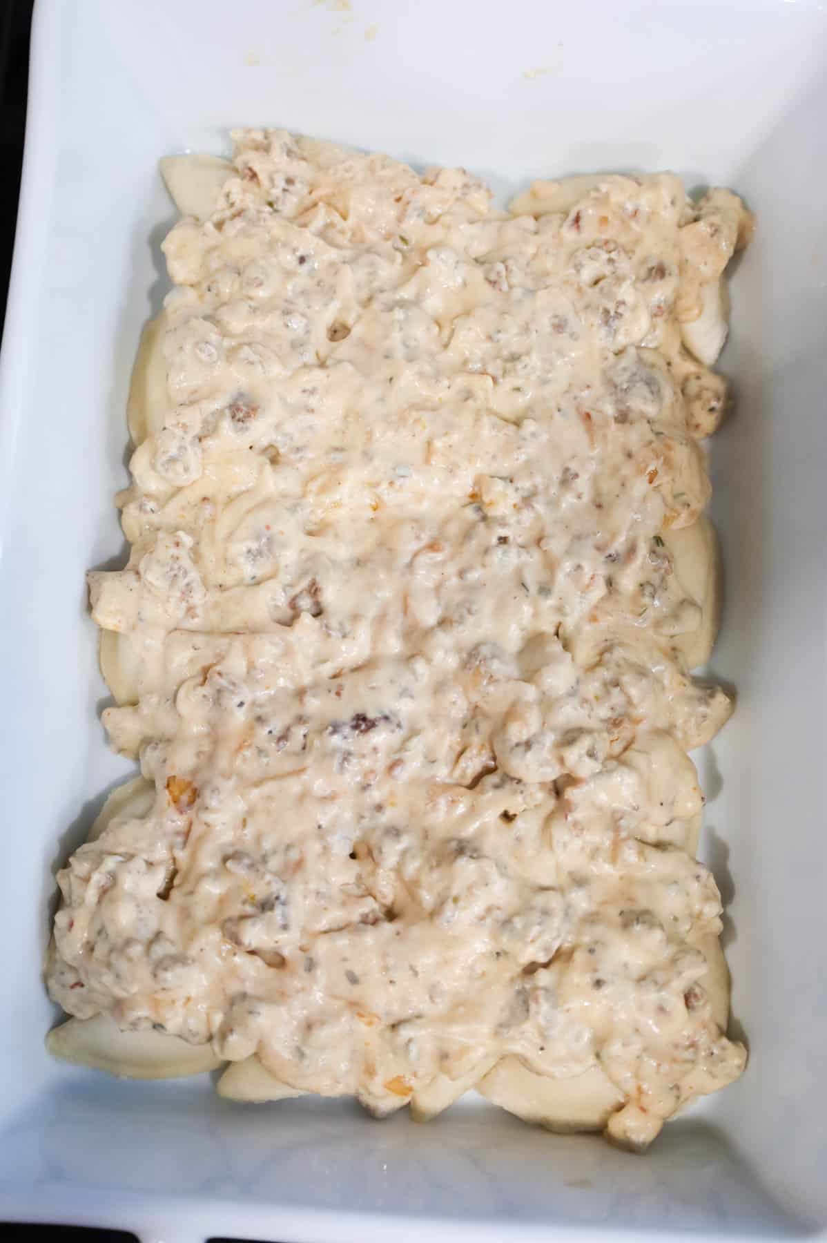 creamy sausage mixture on top of pierogies in a baking dish