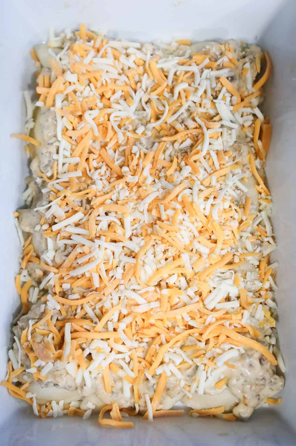 shredded cheese on top of pierogies in a baking dish