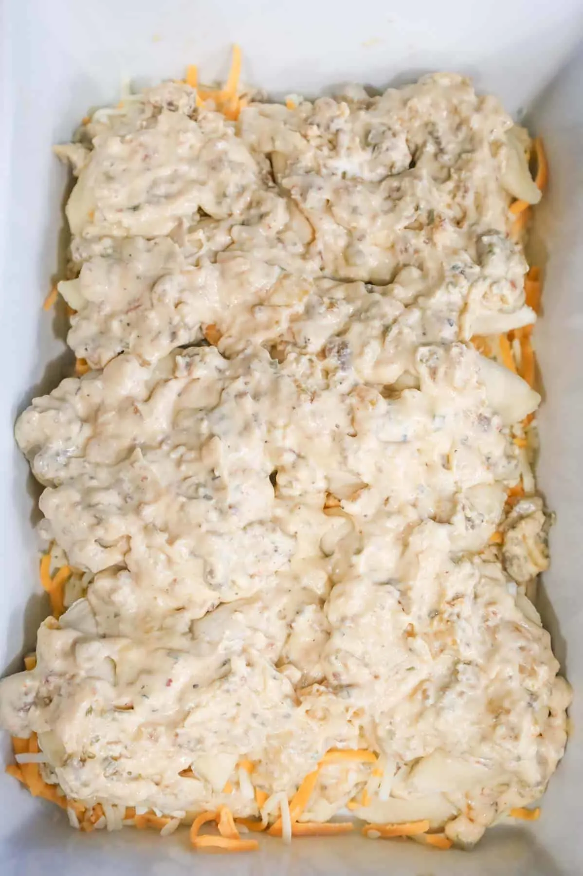 creamy sausage mixture poured over pierogies in a baking dish