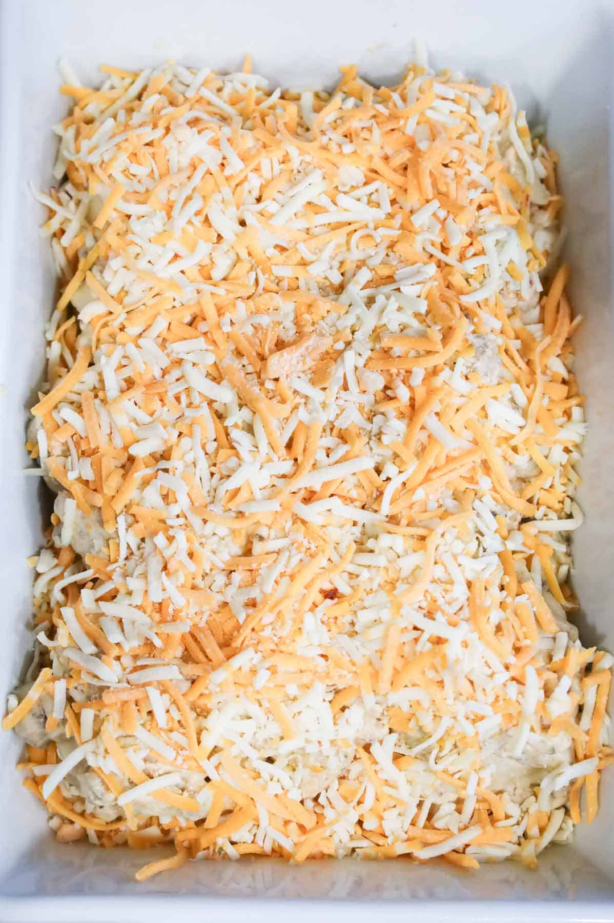 shredded cheese on top of pierogies in a baking dish