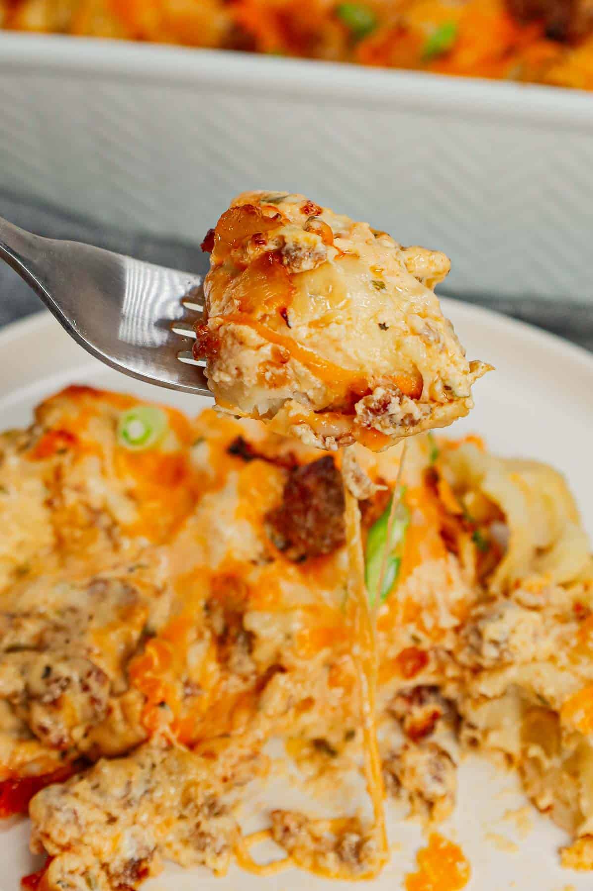 Pierogi Casserole is a hearty dinner recipe loaded with crumbled Italian sausage, onions, three cheese pierogies, cream cheese, Alfredo sauce, shredded mozzarella and cheddar cheese.