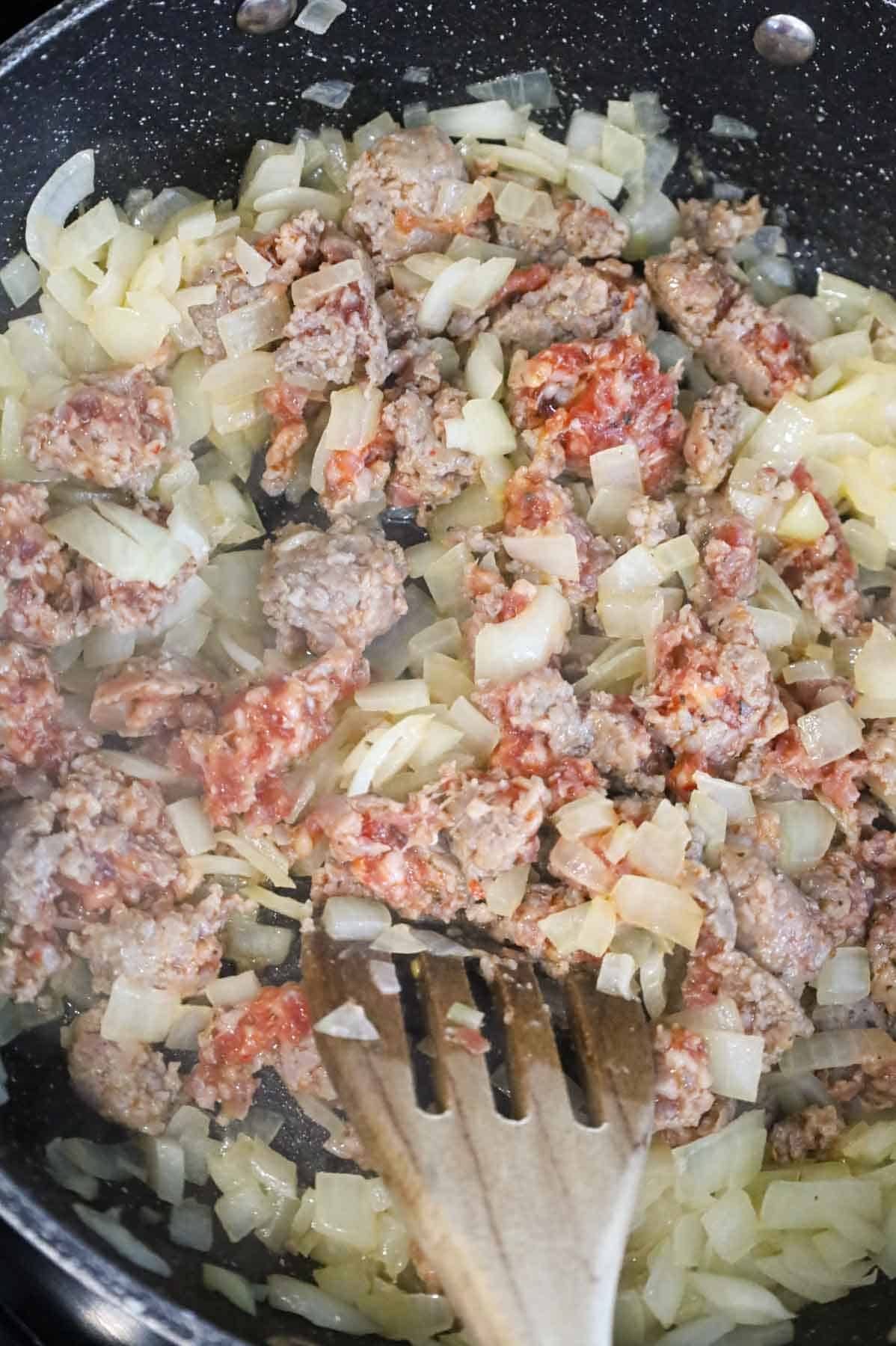 cooking sausage meat and diced onions in a skillet