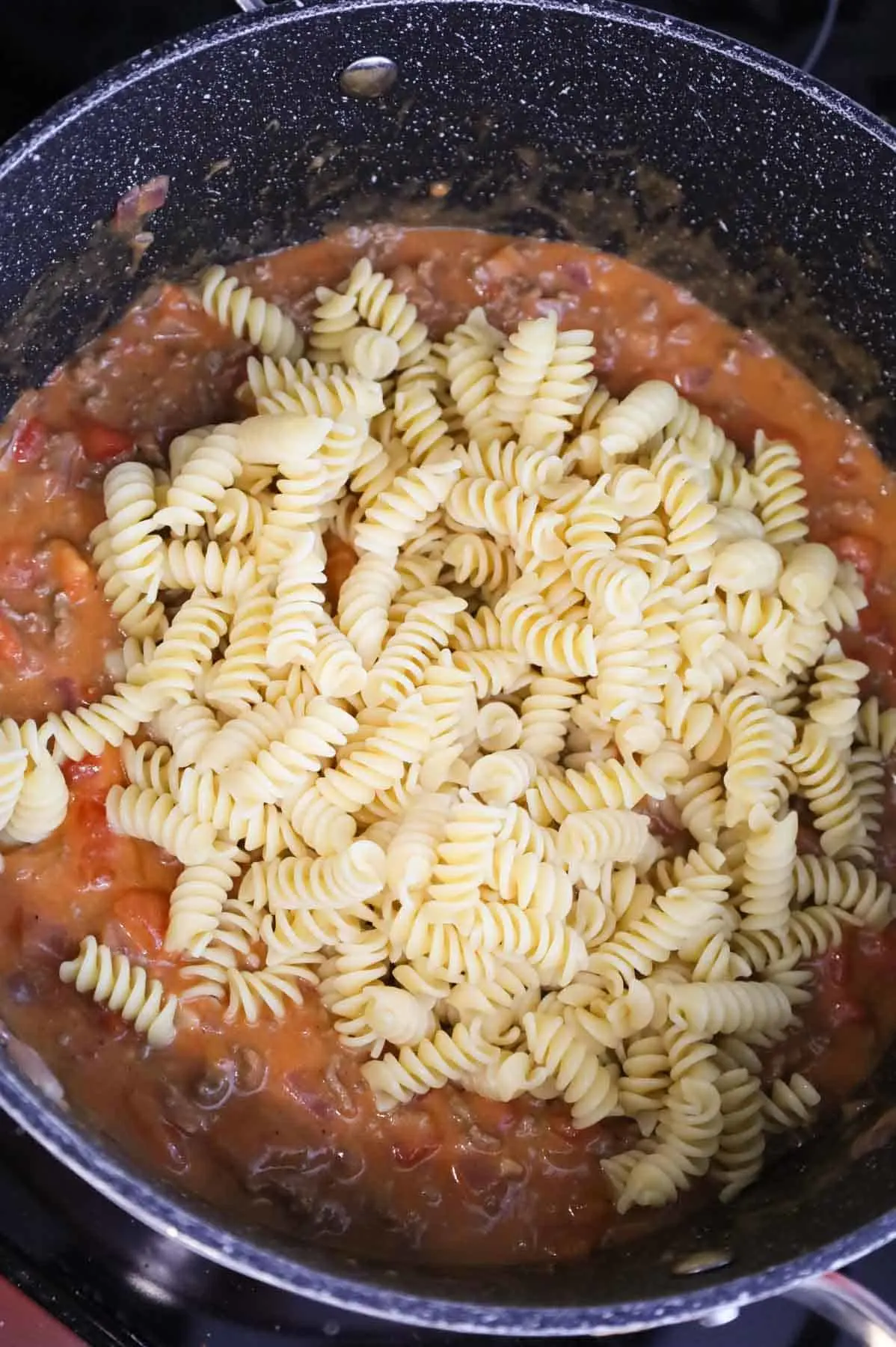 cooked rotini added to pot with ground beef and diced tomato mixture