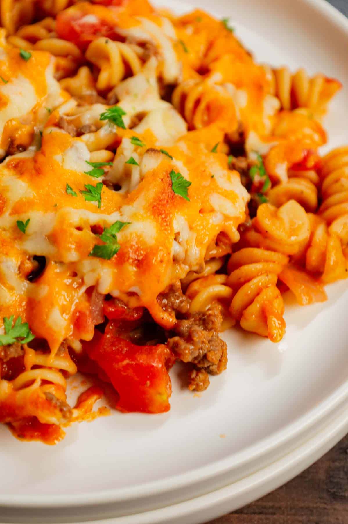 Cheeseburger Casserole is a hearty dish loaded with rotini pasta, ground beef, diced red onions, diced tomatoes, cheddar soup and shredded cheddar cheese.