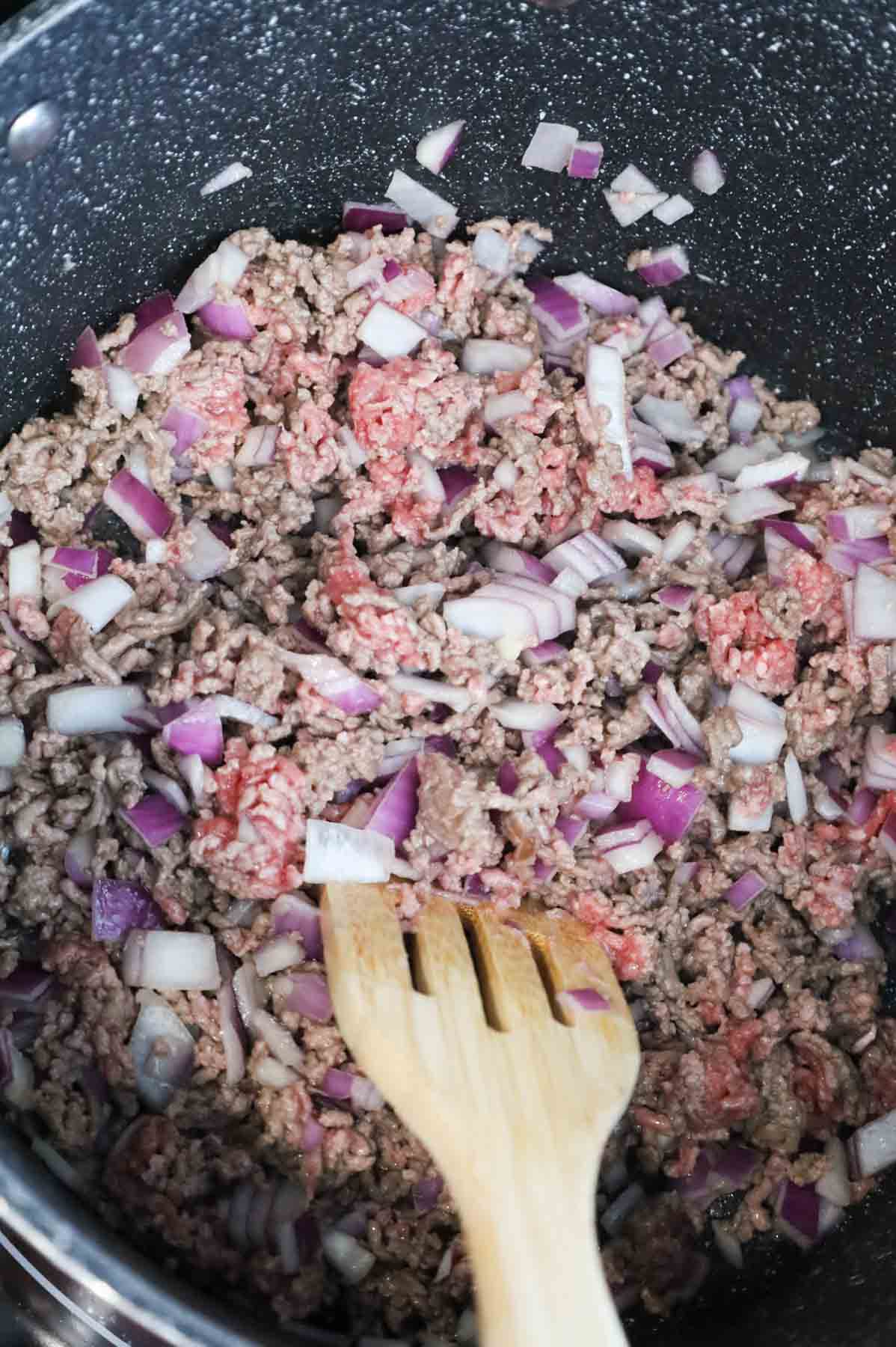 ground beef and diced red onions cooking in a pot