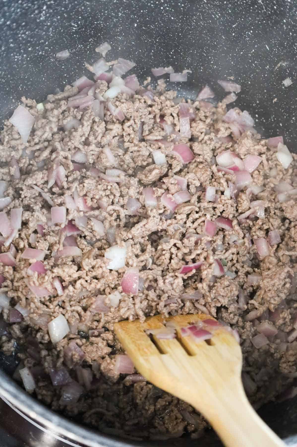 cooked ground beef and diced red onions in a pot