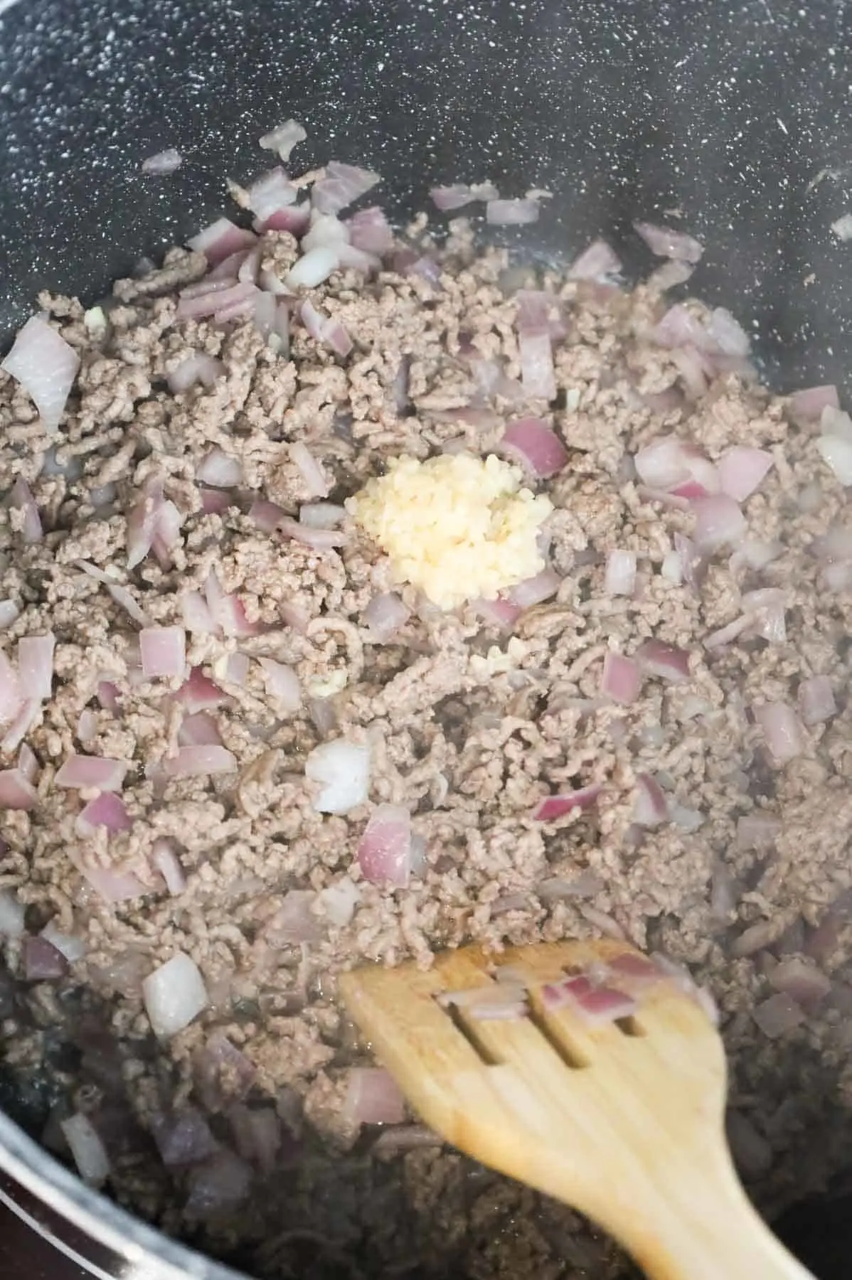 minced garlic added to a pot with cooked ground beef