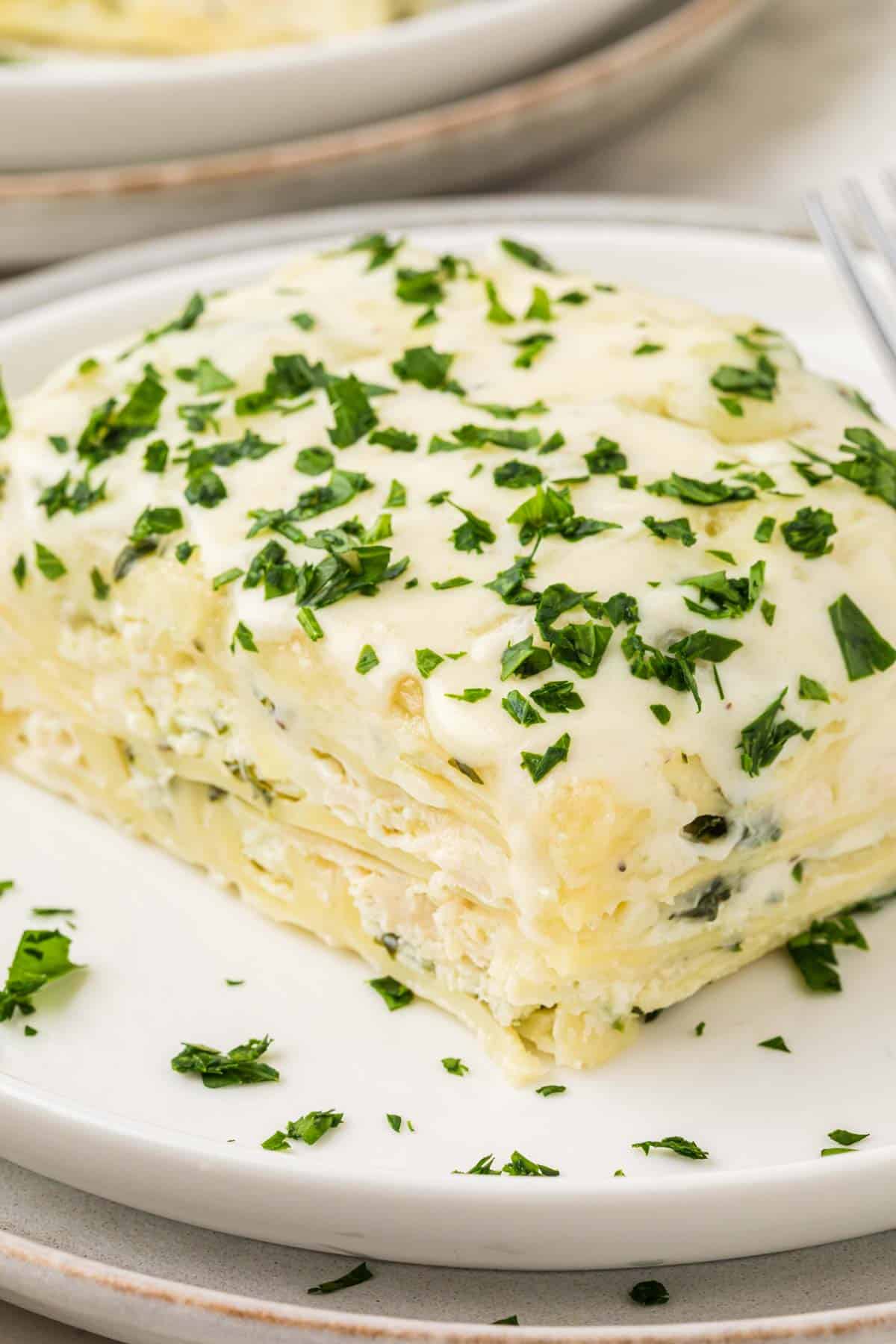 Chicken Alfredo Lasagna is a rich and delicious meal with layers of noodles, ricotta cheese, shredded chicken, mozzarella, sautéed spinach and mushrooms and a creamy Alfredo sauce.