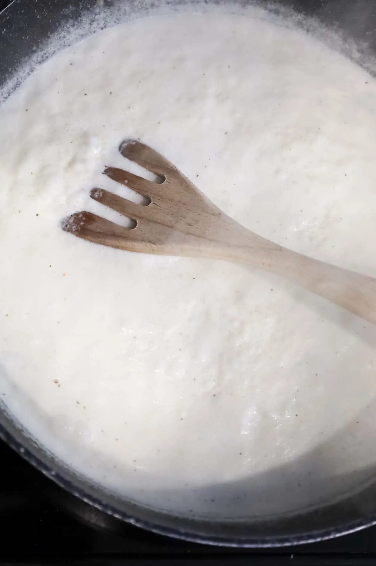 cream sauce being brought to a boil in a skillet