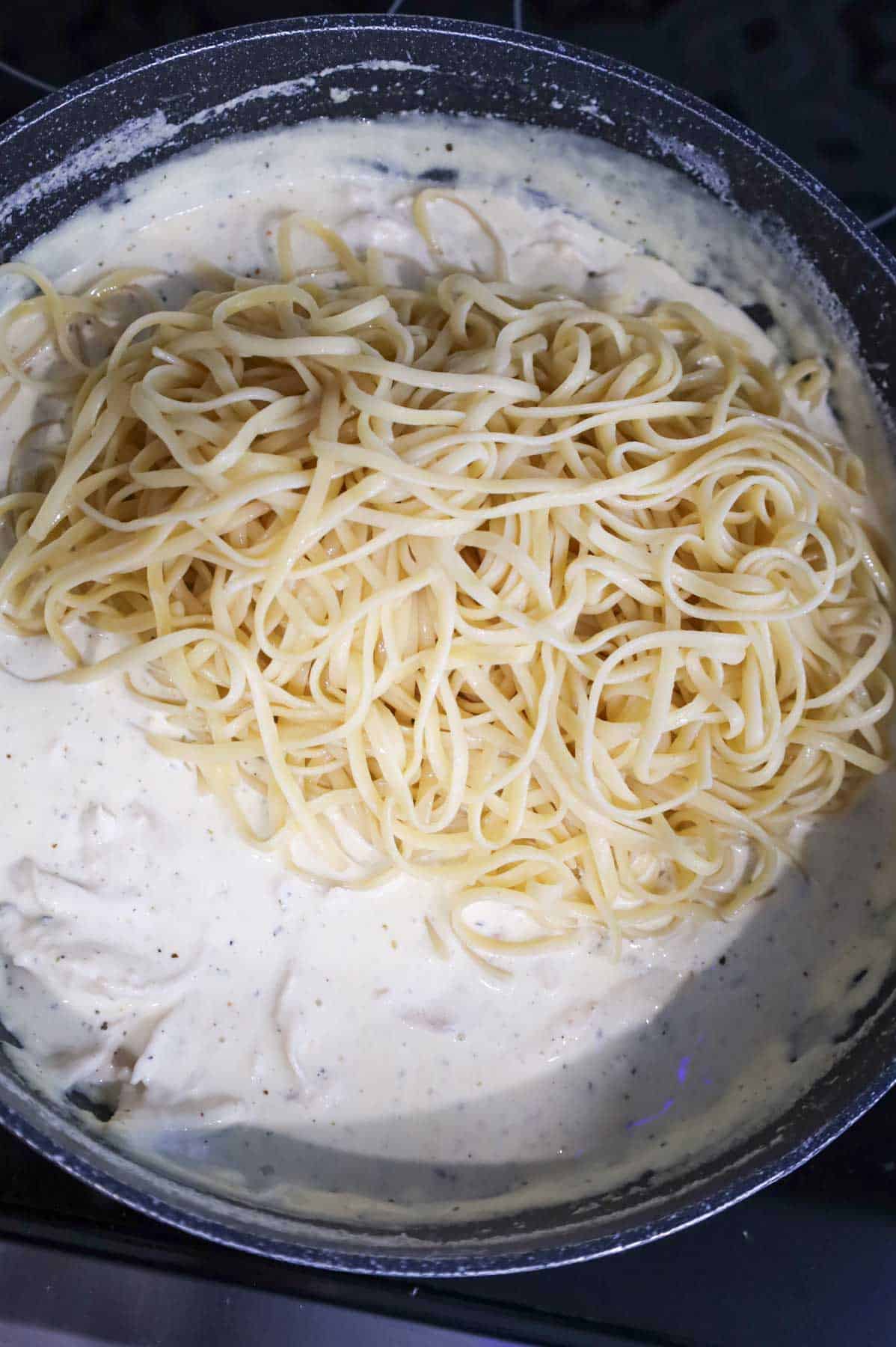 cooked linguine added to skillet with cream sauce