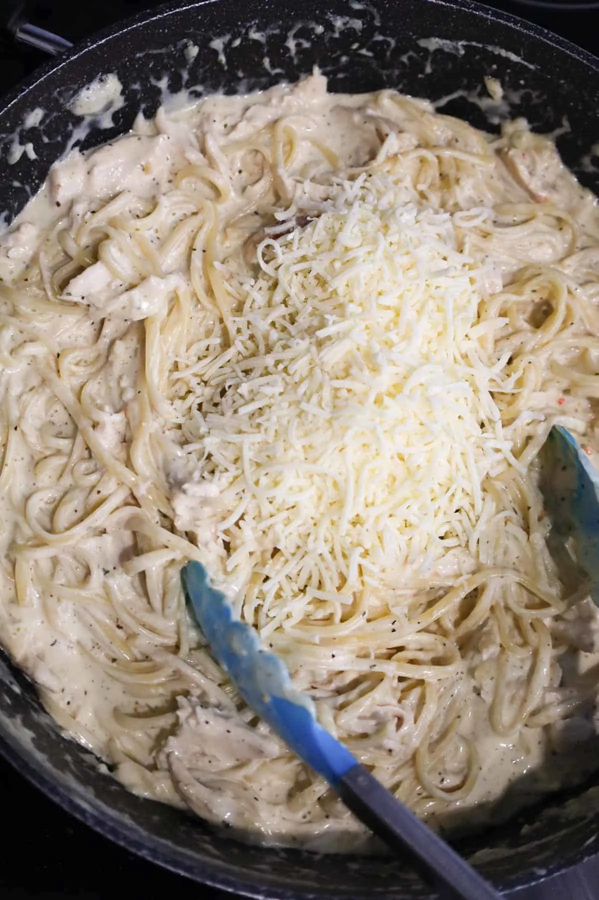 shredded parmesan cheese added to skillet with creamy linguine