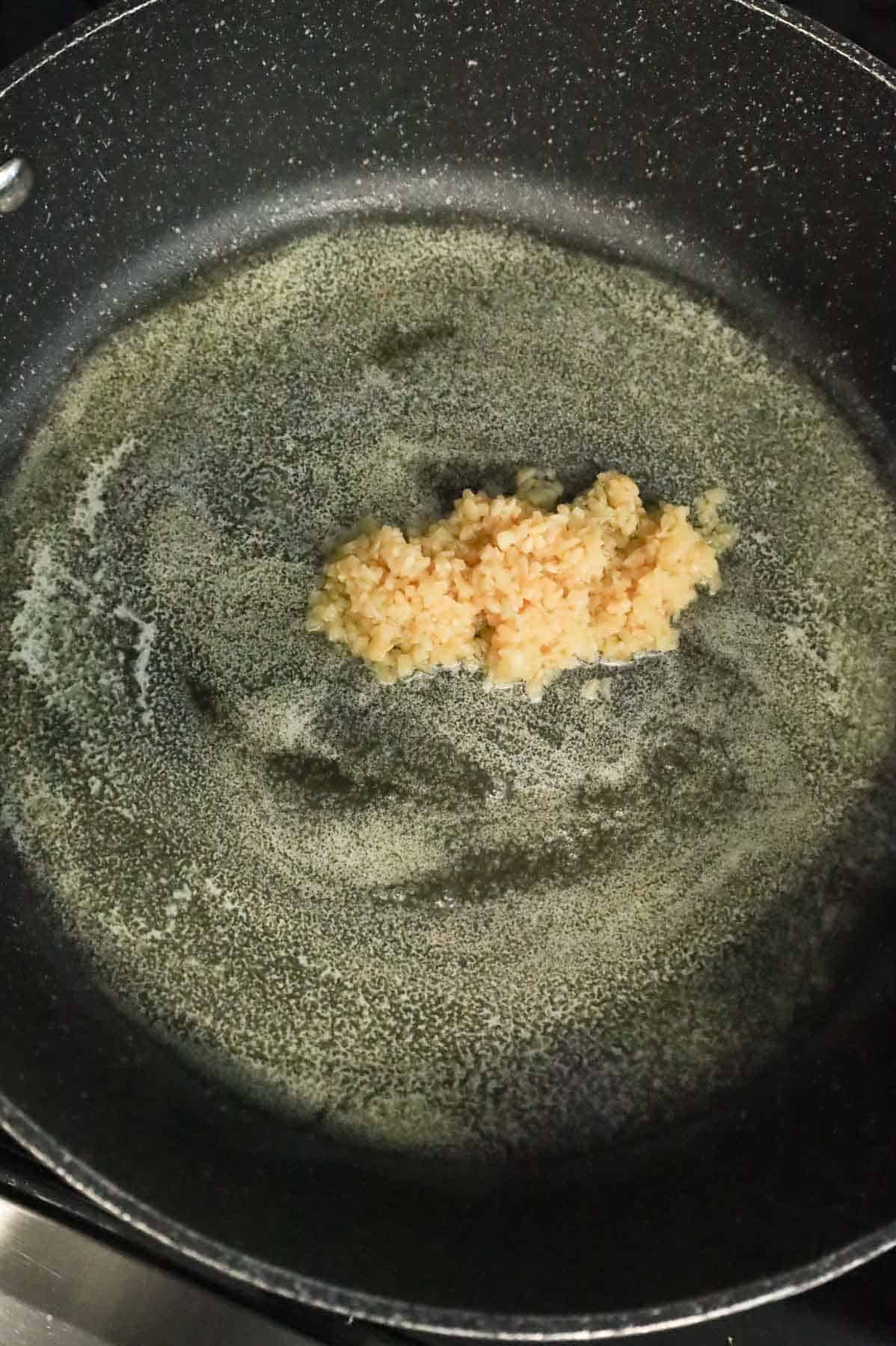 minced garlic added to a skillet with melted butter