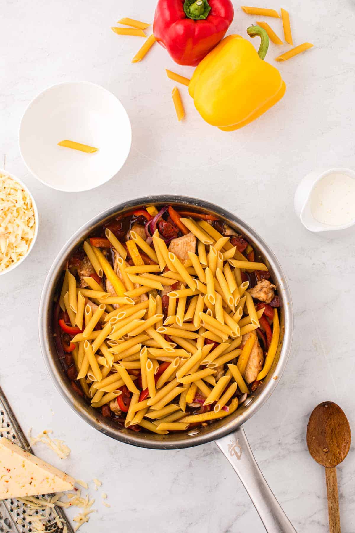 uncooked penne noodles added to pot with broth, chicken breast slices and bell peppers