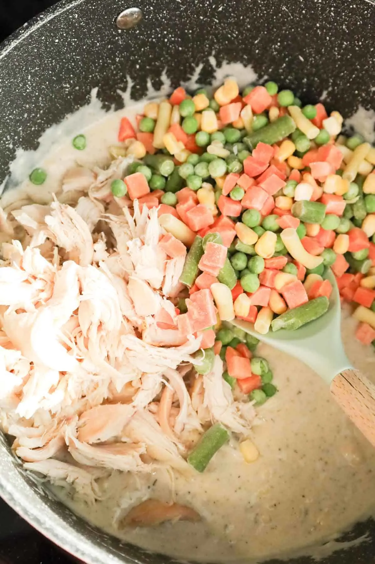 shredded chicken and frozen mixed vegetables added to a pot with creamy soup mixture