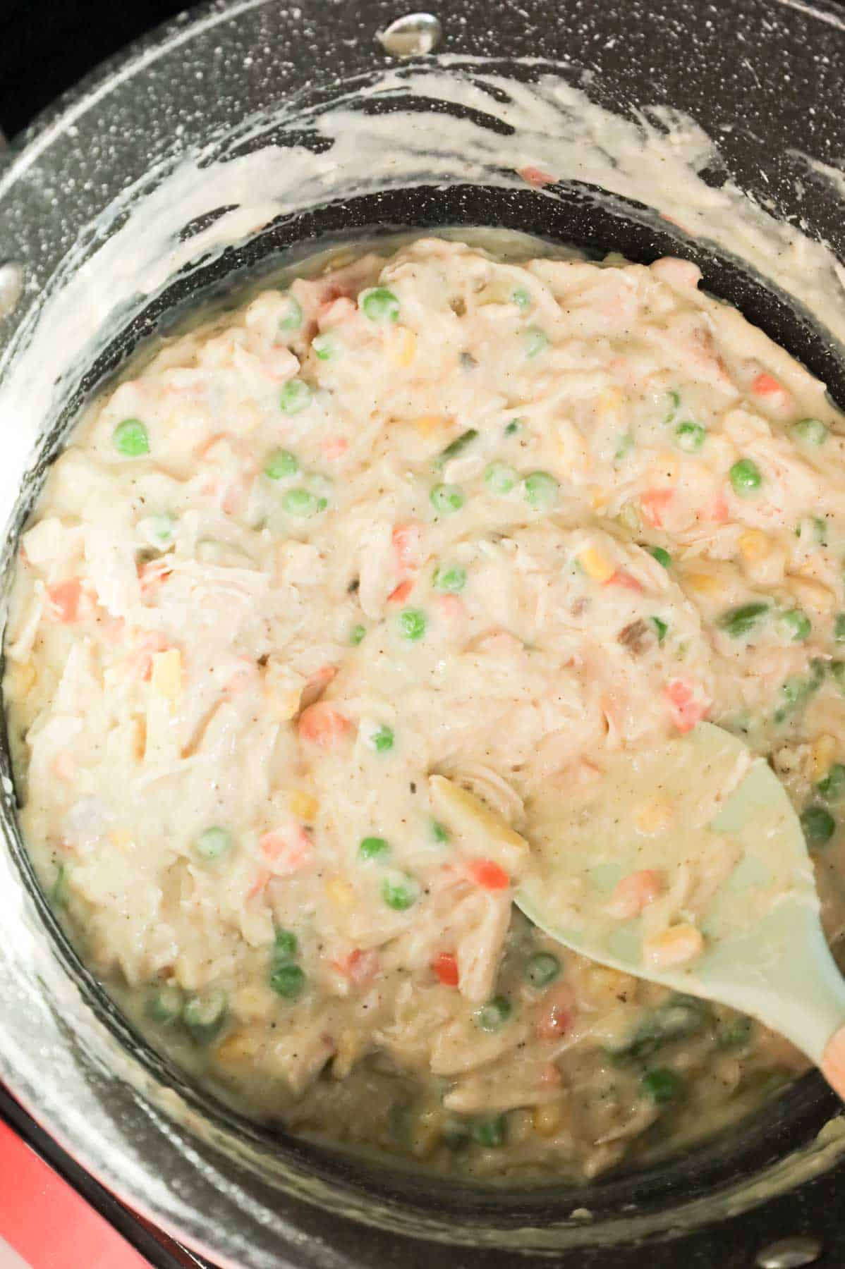stirring creamy chicken and vegetable mixture together in a pot