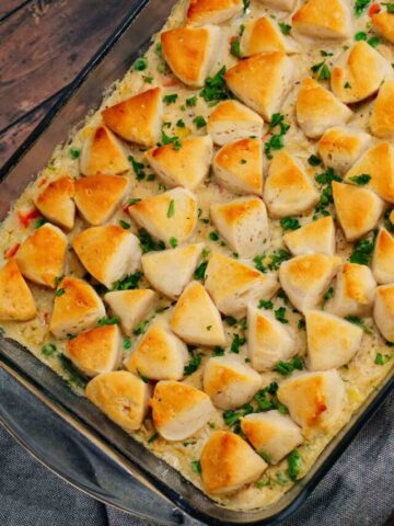 Chicken Pot Pie Casserole is a hearty casserole loaded with shredded rotisserie chicken, frozen mixed vegetables, cream of mushroom soup, cream of chicken soup, milk, grated parmesan cheese and chopped Pillsbury biscuits.