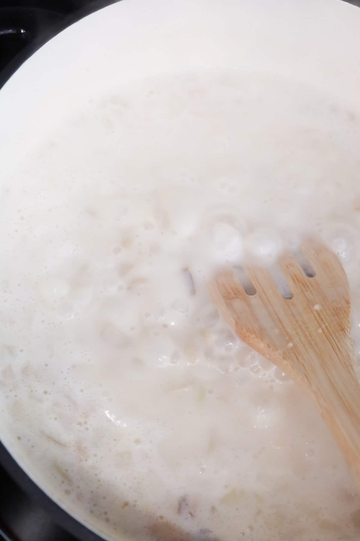 hash brown potato soup simmering in a Dutch oven