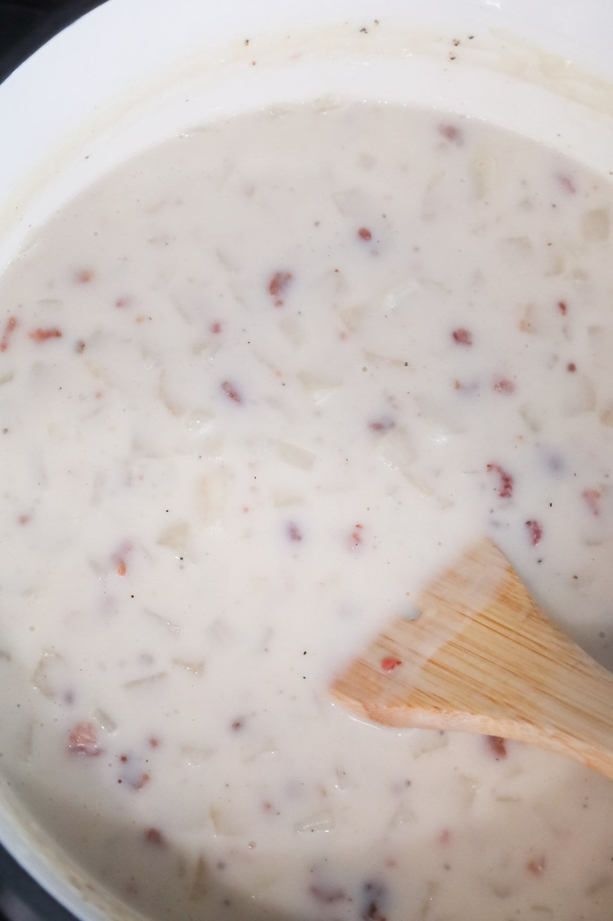 bacon being stirred into creamy potato soup