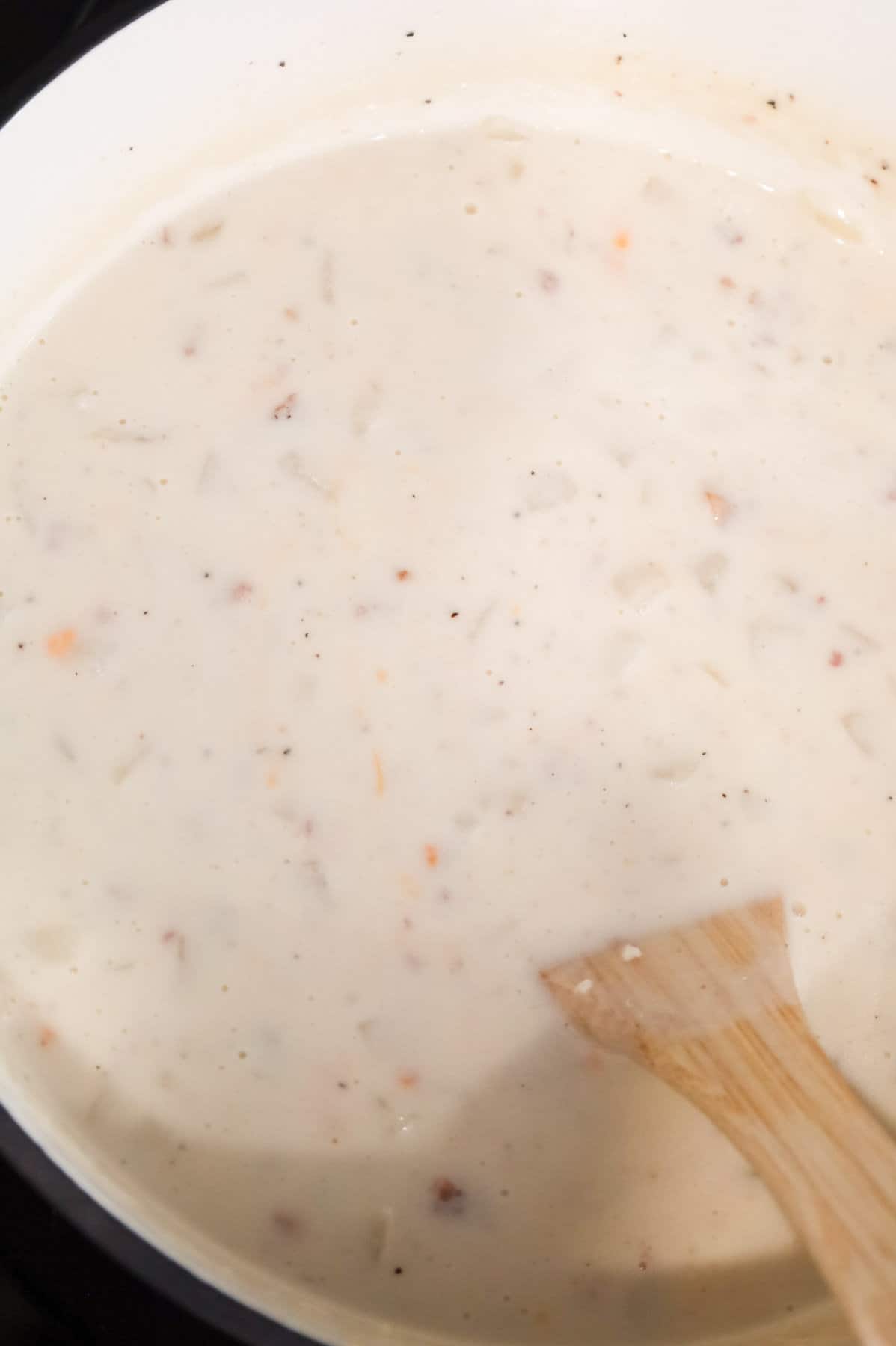 shredded cheese being stirred into potato soup