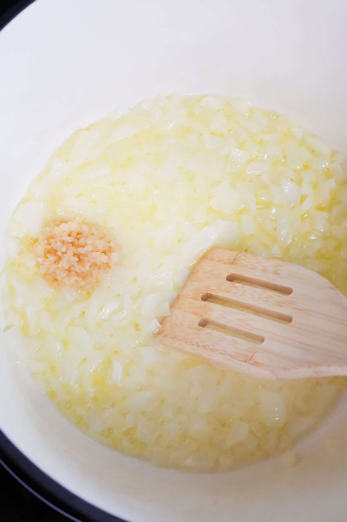 minced garlic added to a pot with diced onions and melted butter