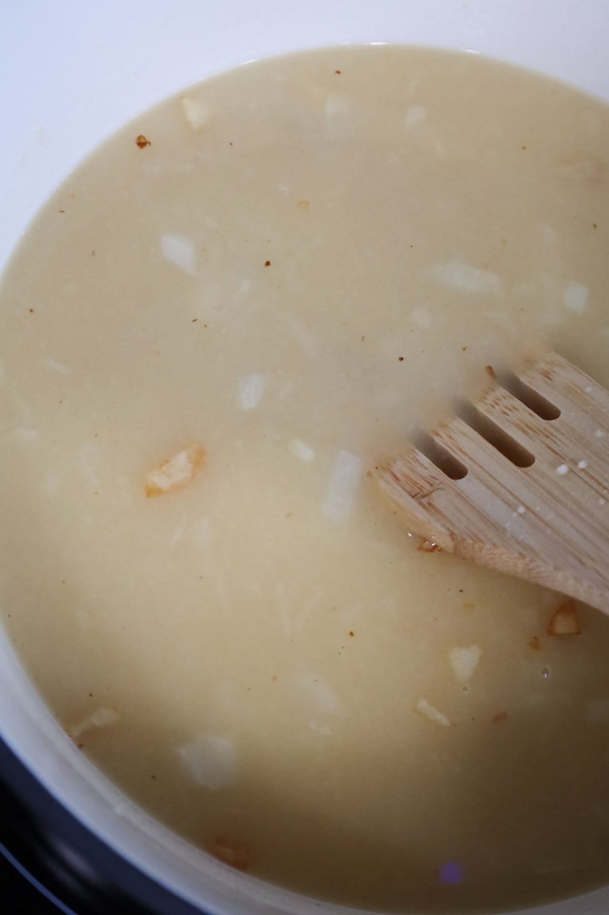 stirring broth into hash brown soup