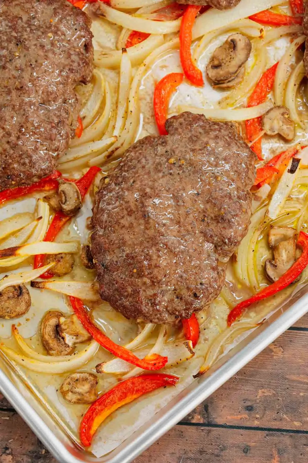 Oven Baked Hamburger Steaks are an easy sheet pan dinner recipe with seasoned ground beef patties cooked along with sliced onions, red bell peppers and mushrooms.