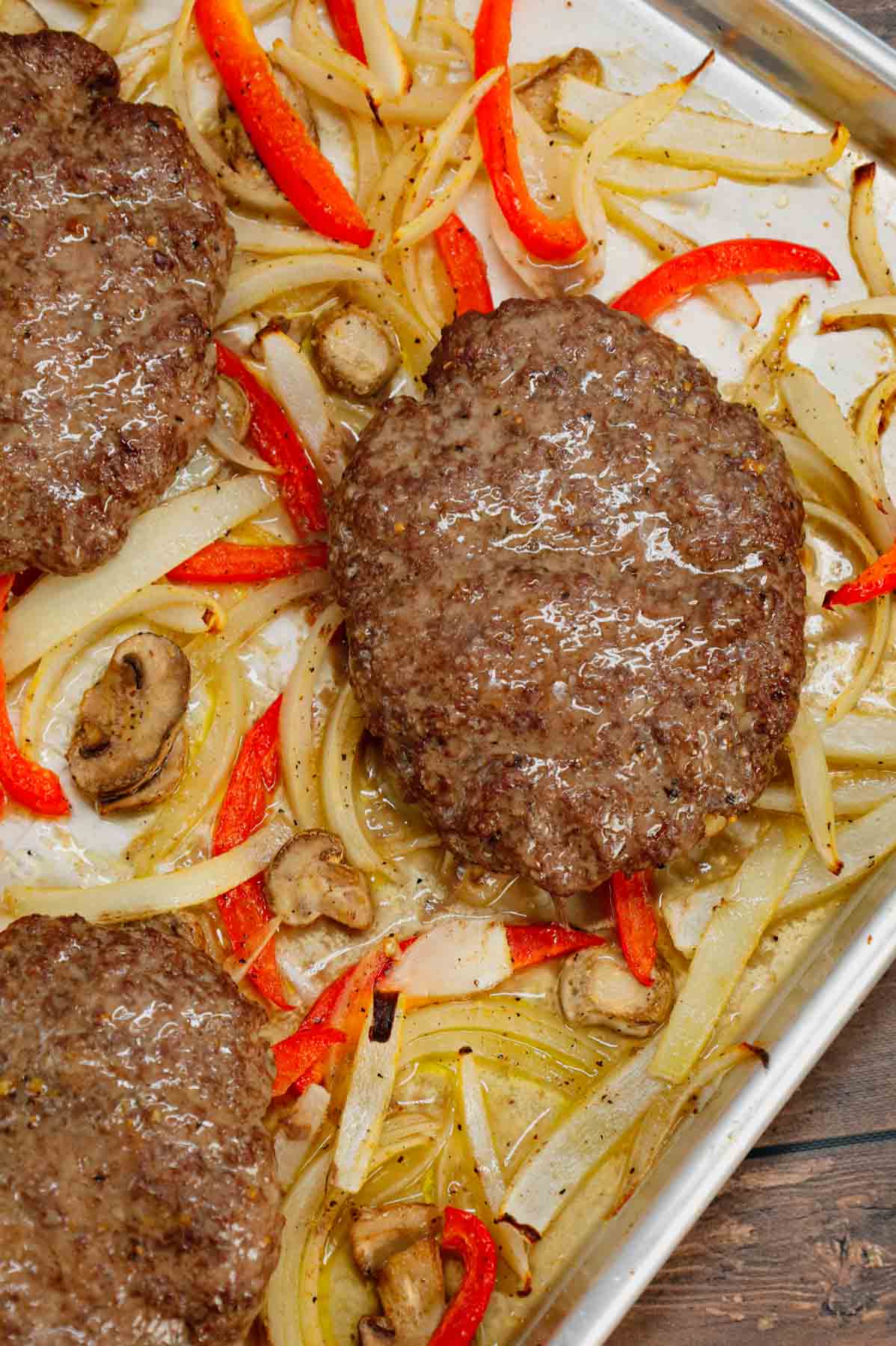 Oven Baked Hamburger Steaks are an easy sheet pan dinner recipe with seasoned ground beef patties cooked along with sliced onions, red bell peppers and mushrooms.