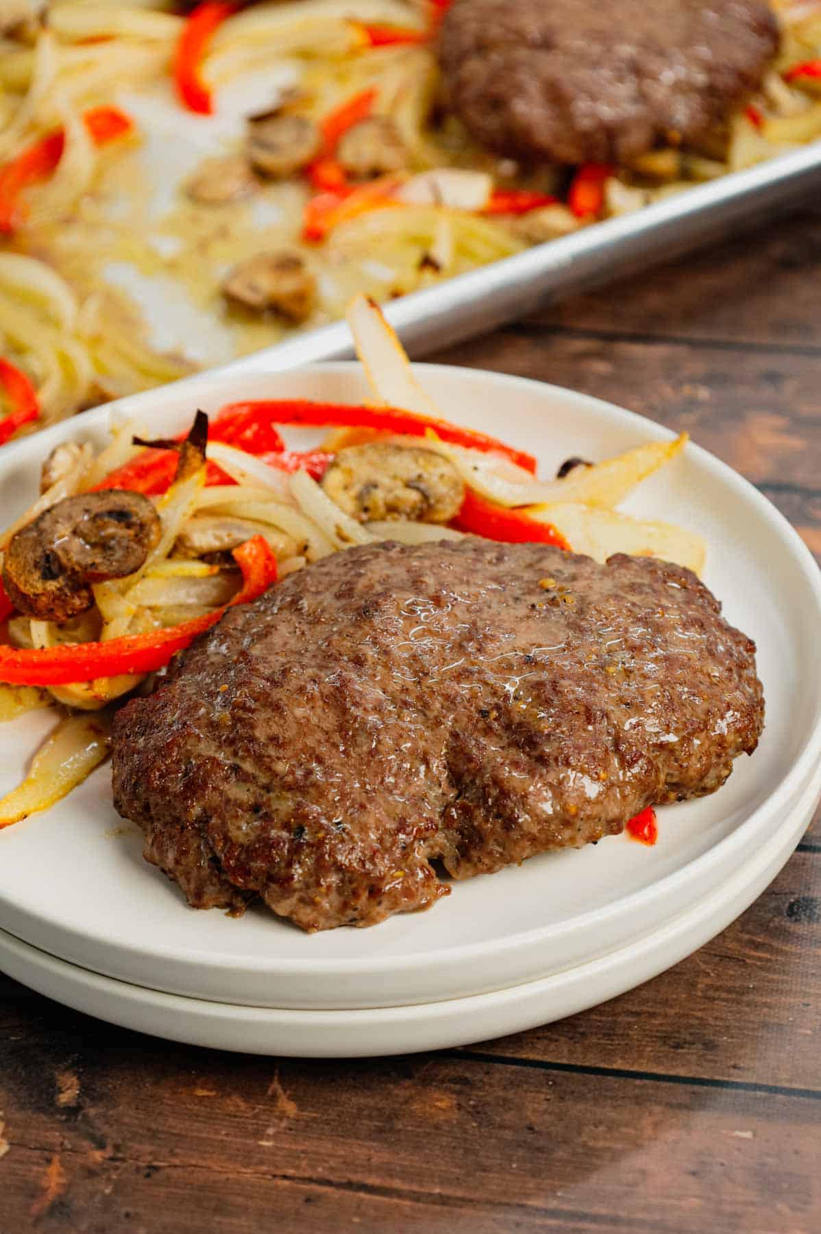 Oven Baked Hamburger Steaks are an easy sheet pan dinner recipe with seasoned ground beef patties cooked along with sliced onions, red bell peppers and mushrooms.