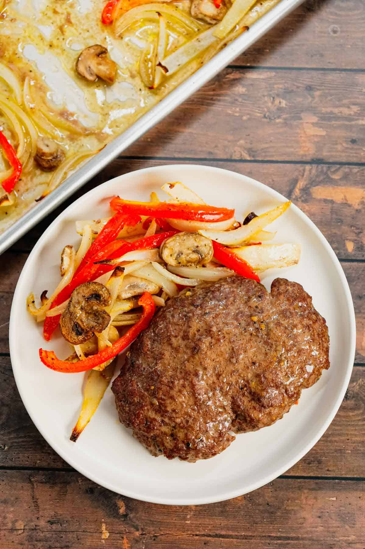 Oven Baked Hamburger Steaks are an easy sheet pan dinner recipe with seasoned ground beef patties cooked along with sliced onions, red bell peppers and mushrooms.