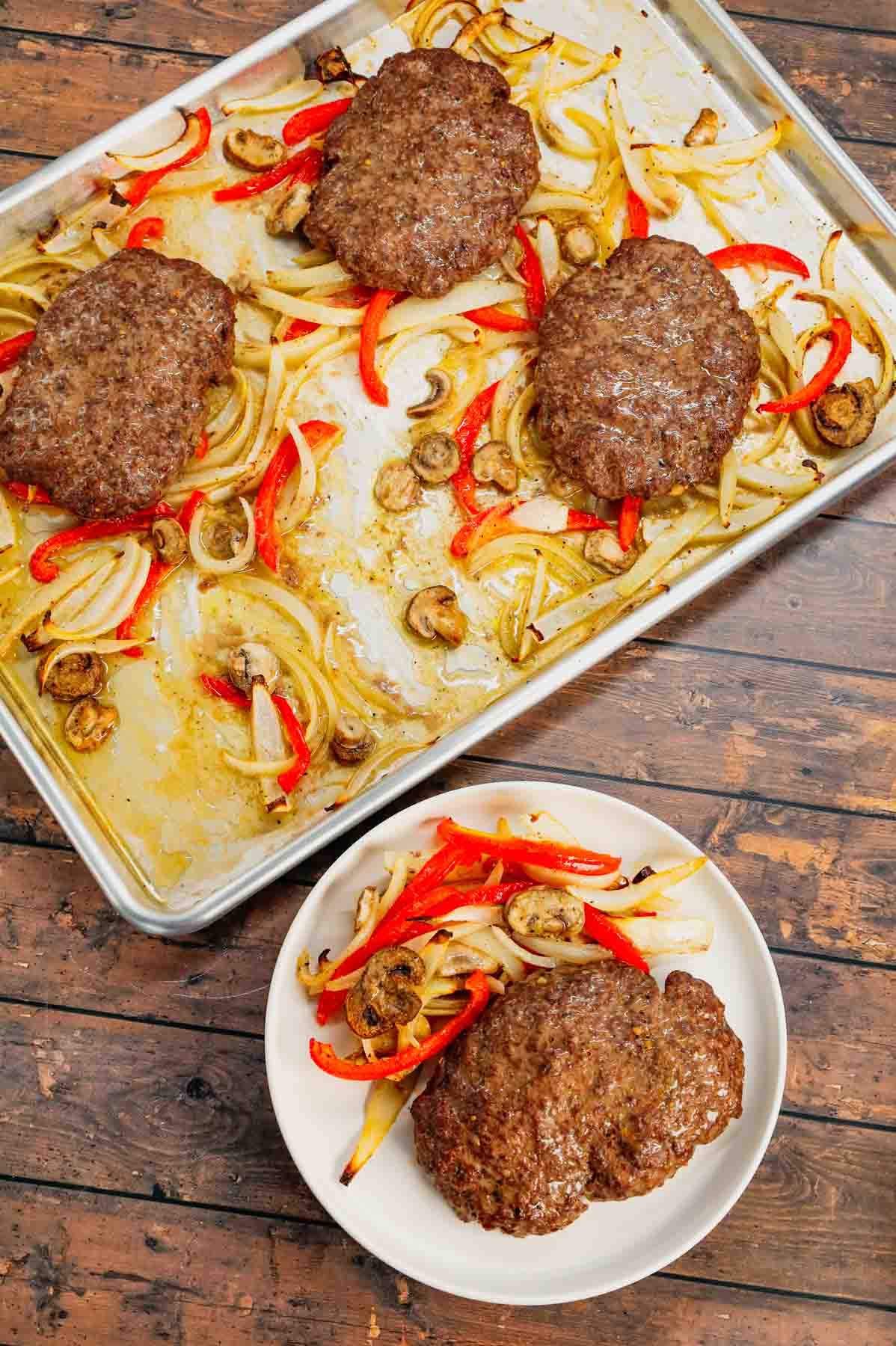 Oven Baked Hamburger Steaks are an easy sheet pan dinner recipe with seasoned ground beef patties cooked along with sliced onions, red bell peppers and mushrooms.