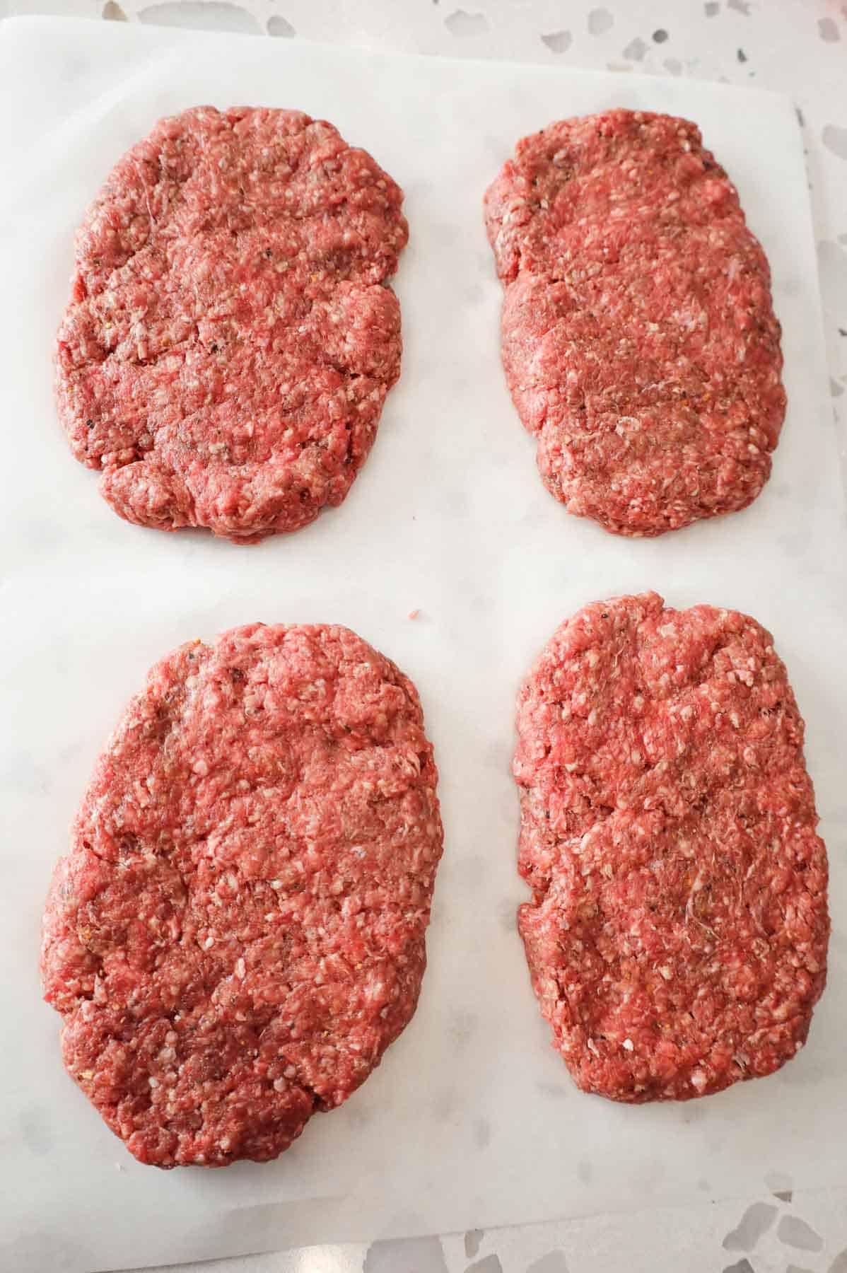 raw ground beef patties on parchment paper