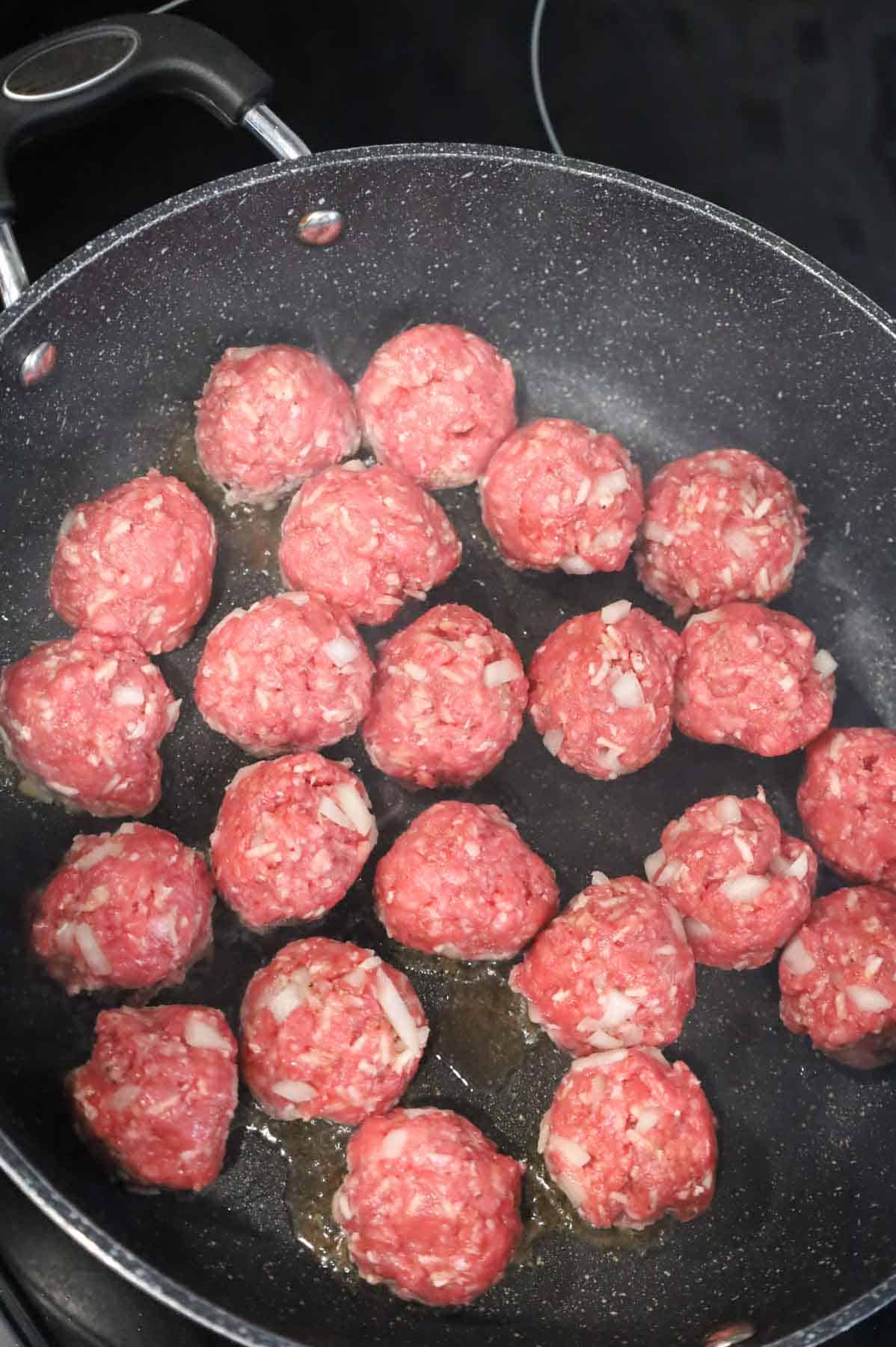 raw meatballs added to a hot skillet