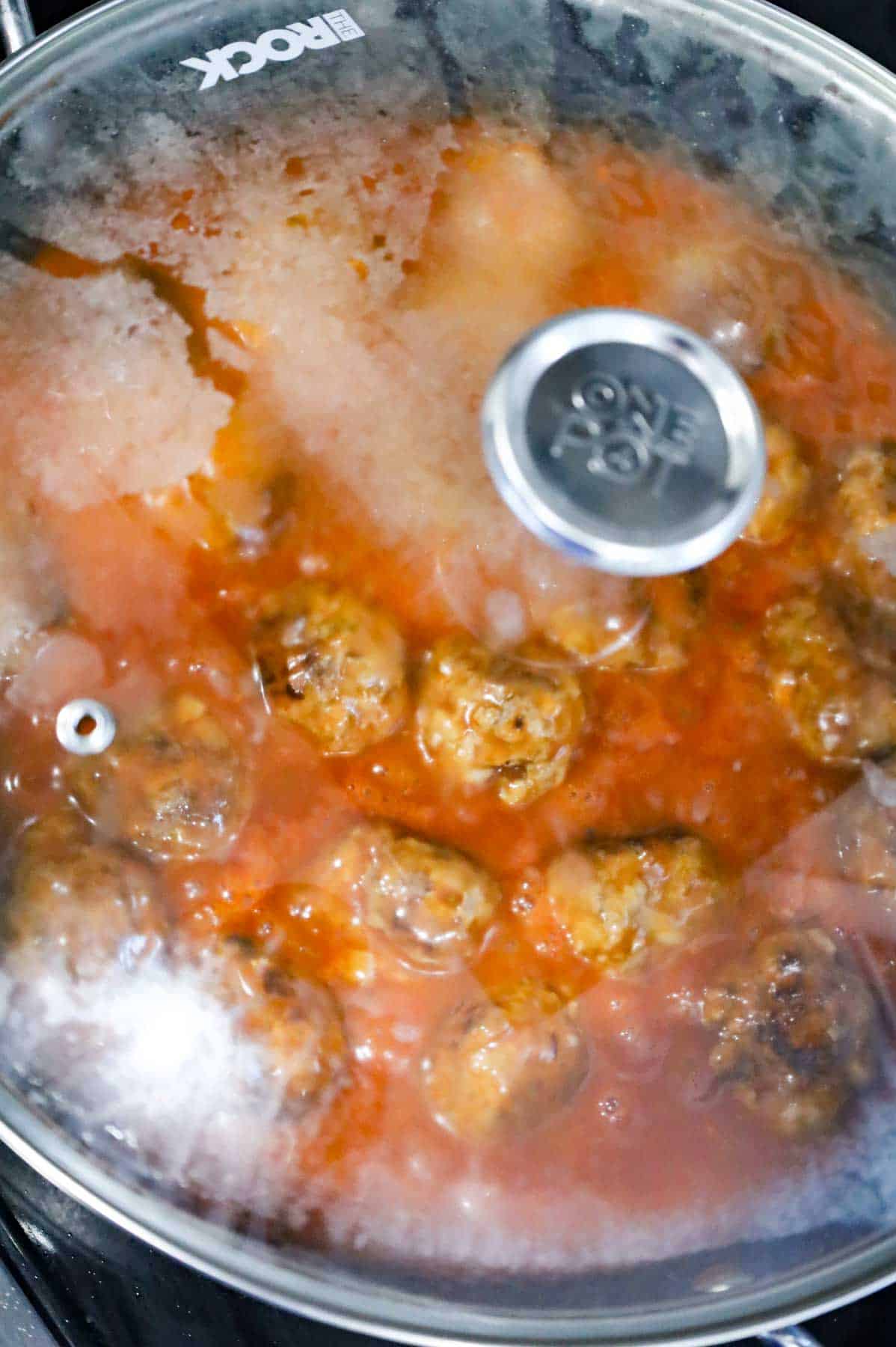 lid on skillet with porcupine meatballs and tomato sauce simmering