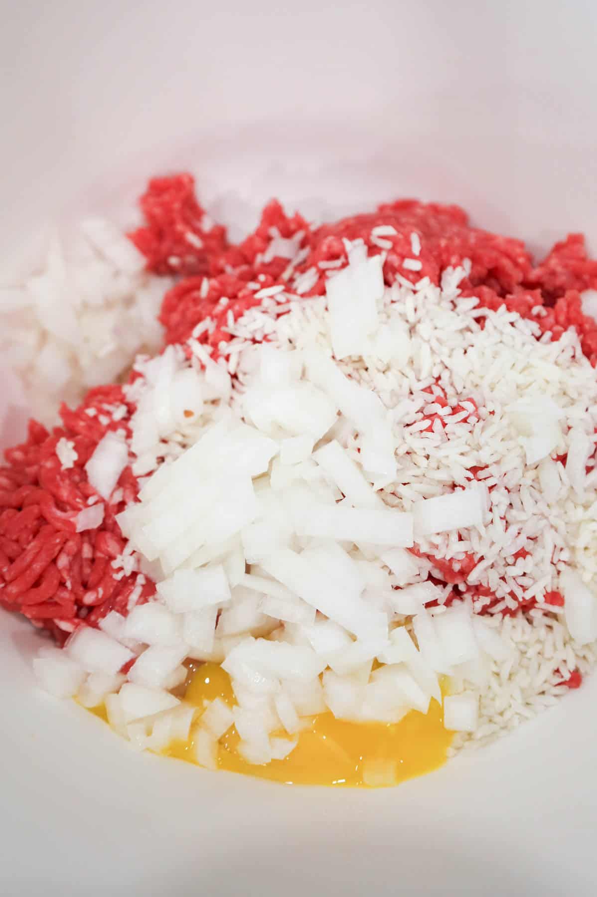 diced onions, minute rice, egg and ground beef in a bowl