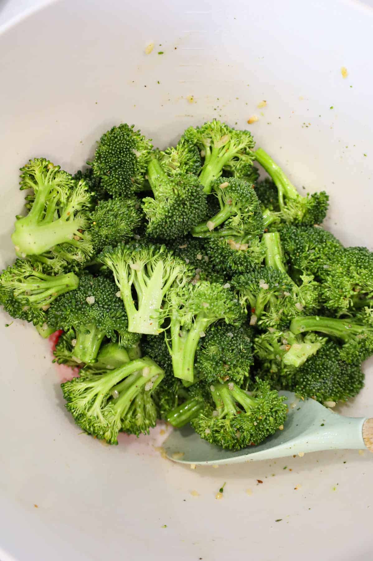 broccoli florets in a bowl tossed in olive oil and seasonings