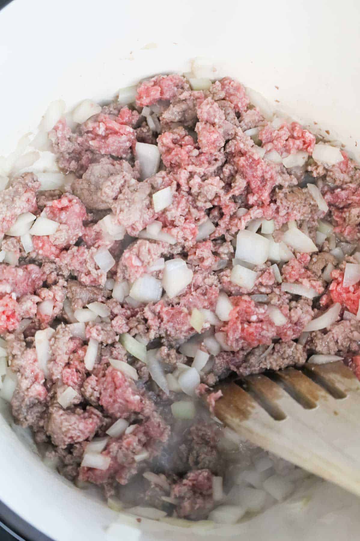 ground beef and diced onions cooking in a Dutch oven