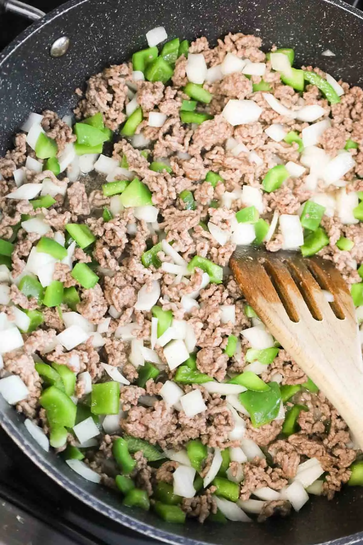 ground beef, diced onions and bell peppers cooking in a skillet