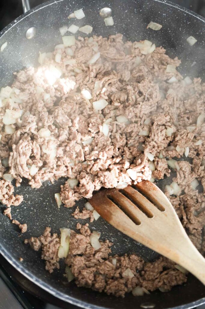 stirring ground beef and diced onions together in a skillet