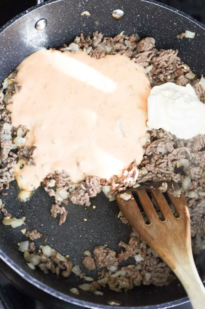 Thousand Island dressing and mayo on top of cooked ground beef in a skillet