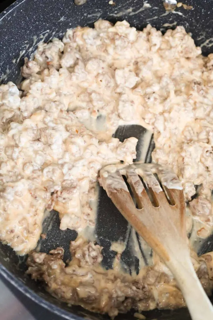 ground beef being stirred with mayo and Thousand Island dressing in a skillet