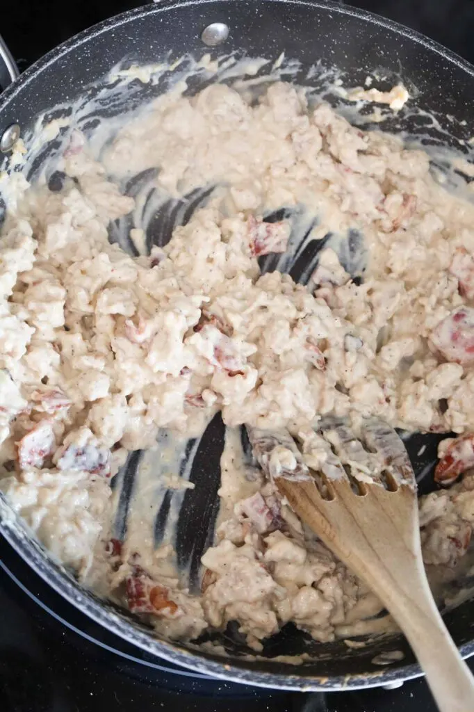 stirring bacon and parmesan cheese into creamy chicken alfredo mixture