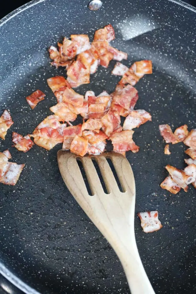 crispy bacon pieces cooking in a skillet