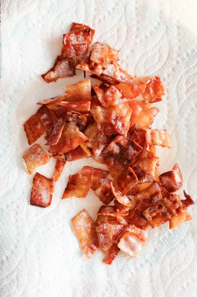 cooked bacon pieces on a paper towel lined plate