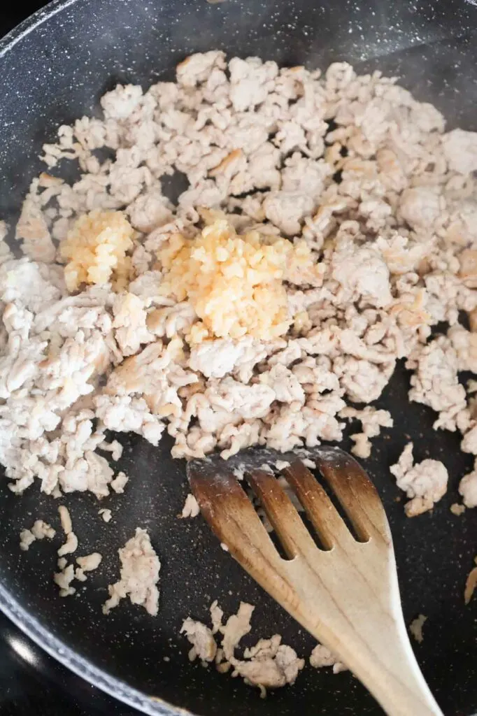minced garlic added to skillet with cooked ground chicken