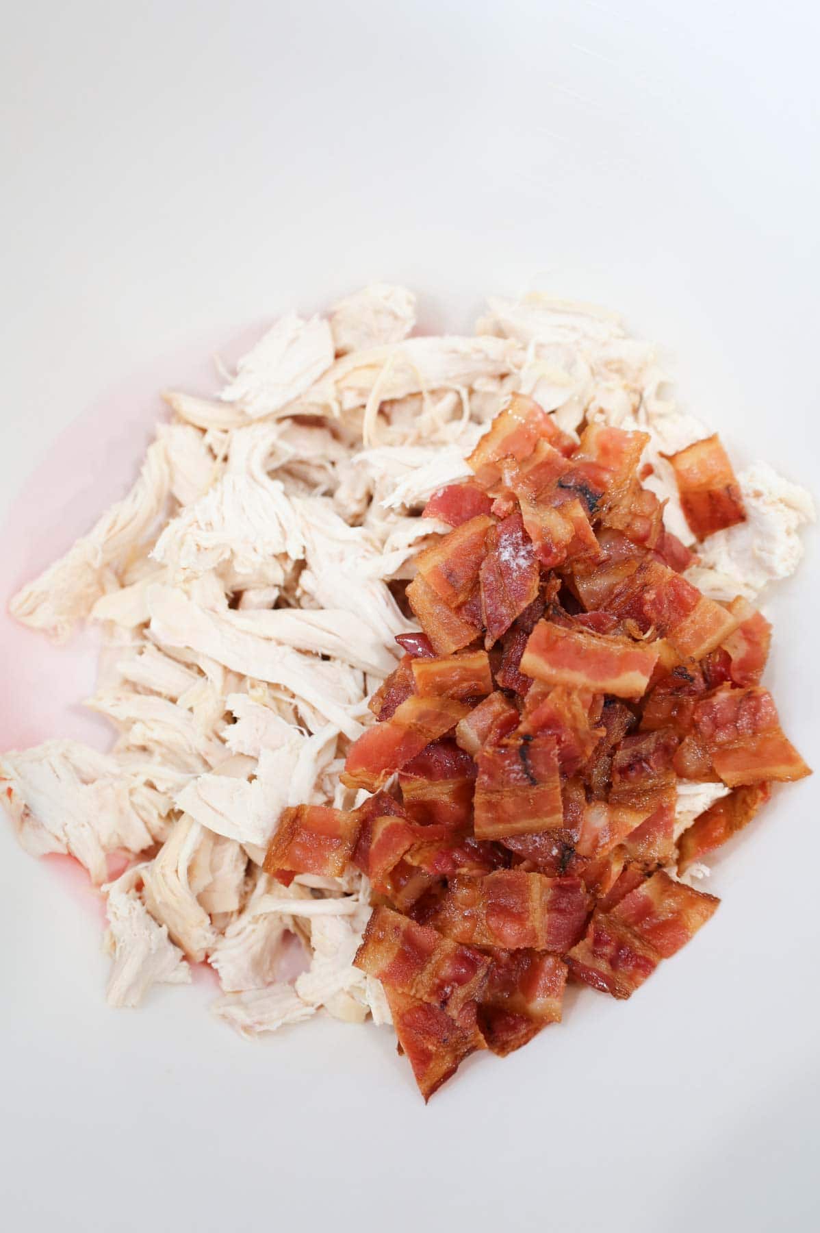 shredded chicken and chopped bacon in a mixing bowl
